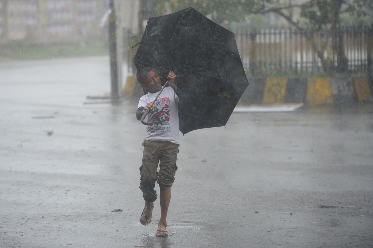 A boy struggles with an umbrella on a street under heavy rain as cyclone Bulbul approaches the area in Khulna on 10 November 2019. Photo: AFP