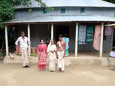 A view of the widow of Mongol Chandra Sarker (in white sari) with her daughter and son in front of the family`s tin house in central Bangladesh`s Ghior sub-district, on 1 September 2019. Photo: Thomson Reuters Foundation