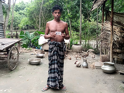 Mojibur Rahman, injured by lightning, poses with his national identity card in front of his tin shed in Ghior, Bangladesh, on 1 September 2019. Photo: Thomson Reuters Foundation