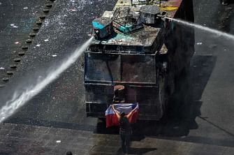 Aerial view of a demonstratopr standing in front of a police water cannon with a Chilean national flag in Santiago on 12 November 2019. Photo: AFP