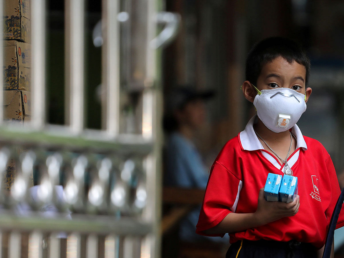 A student wears a mask as he waits to be picked up, as classes in over 400 Bangkok schools have been cancelled due to worsening air pollution, at a public school in Bangkok, Thailand on 30 January. Photo: AFP