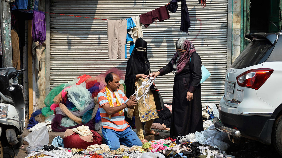 A vendor selling various items on the street attends customers in the old quarters of New Delhi on 10 November. Photo” AFP