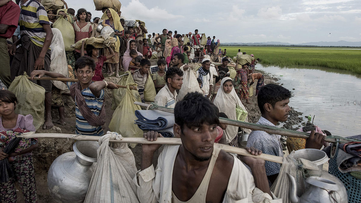 In this file photo taken on 9 October 2017, Rohingya refugees walk with their belongings after crossing the Naf river from Myanmar into Bangladesh in Whaikhyang. Photo: AFP