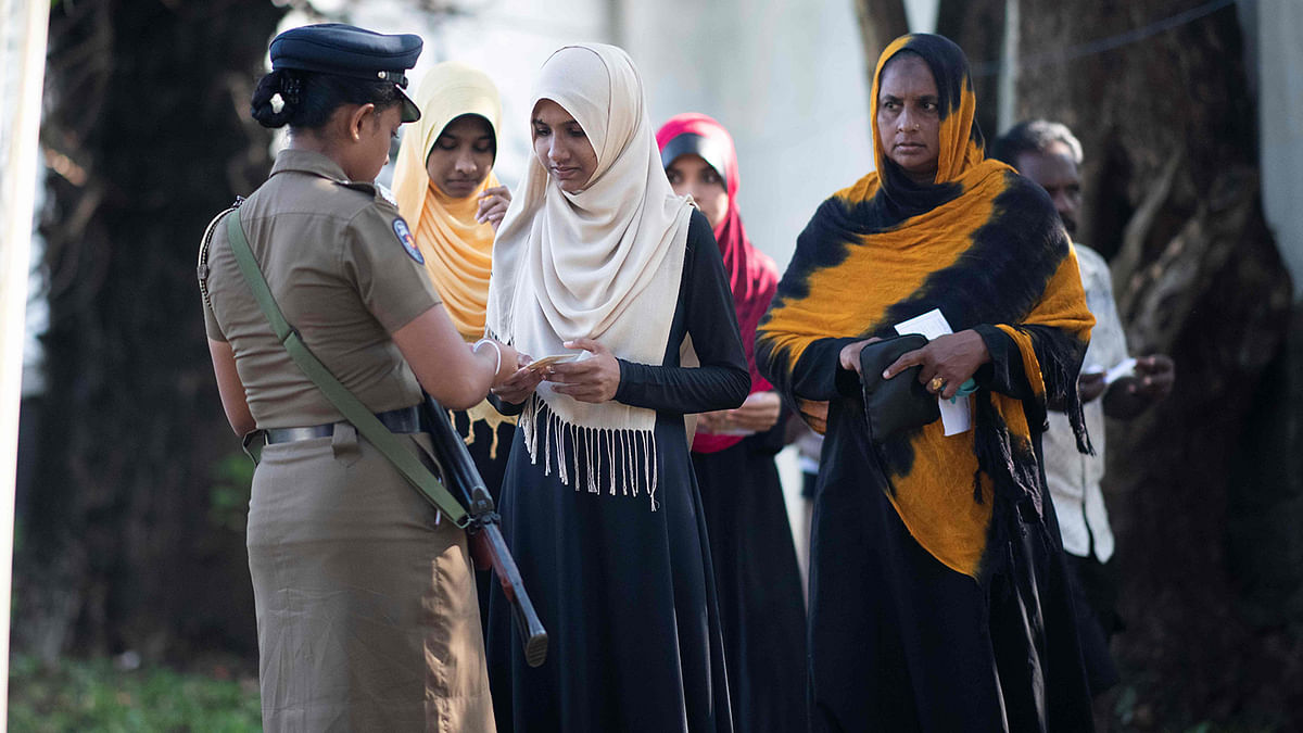 A policewoman checks voter`s registration cards as they arrive at a polling station set up on the premises of a Buddhist temple to cast their ballots during Sri Lanka`s presidential election in Colombo on 16 November 2019. Photo: AFP