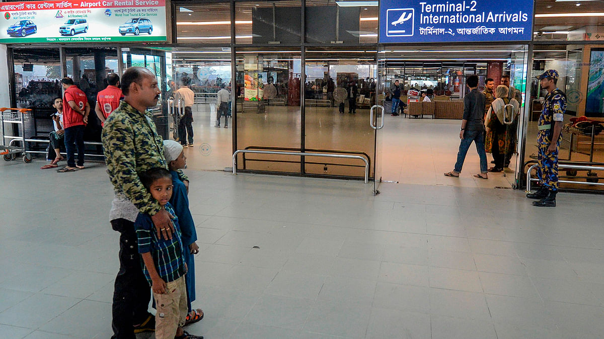 Nurul (Siraj) Islam along with his two kids wait to receive his wife Sumi Akter at Hazrat Shahjalal International Airport in Dhaka on 15 November 2019. Photo: AFP