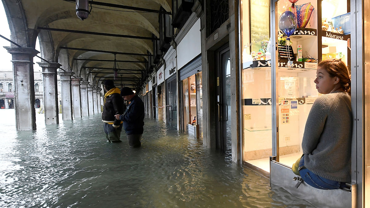 A woman looks on from a shop at the flooded St. Mark`s Square, as high tide reaches peak, in Venice, Italy on 15 November 2019. Photo: Reuters