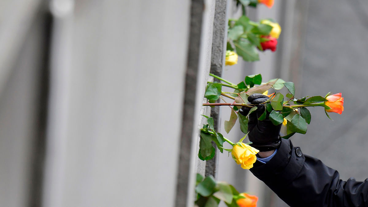 A man places a flower at the Berlin Wall Memorial during the central commemoration ceremony for the 30th anniversary of the fall of the Berlin Wall, on 9 November 2019 at the Berlin Wall Memorial at Bernauer Strasse in Berlin. Photo: AFP