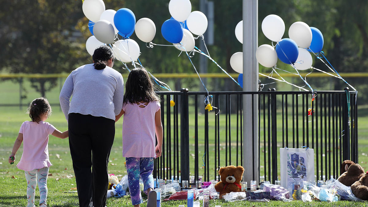 A woman and two girls visit a makeshift memorial in Central Park to victims of the shooting at nearby Saugus High School on 15 November 2019 in Santa Clarita, California. Photo: AFP