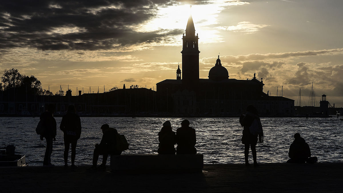 People watch the sunset over San Giorgio Maggiore on 14 November 2019 in Venice. Photo: AFP