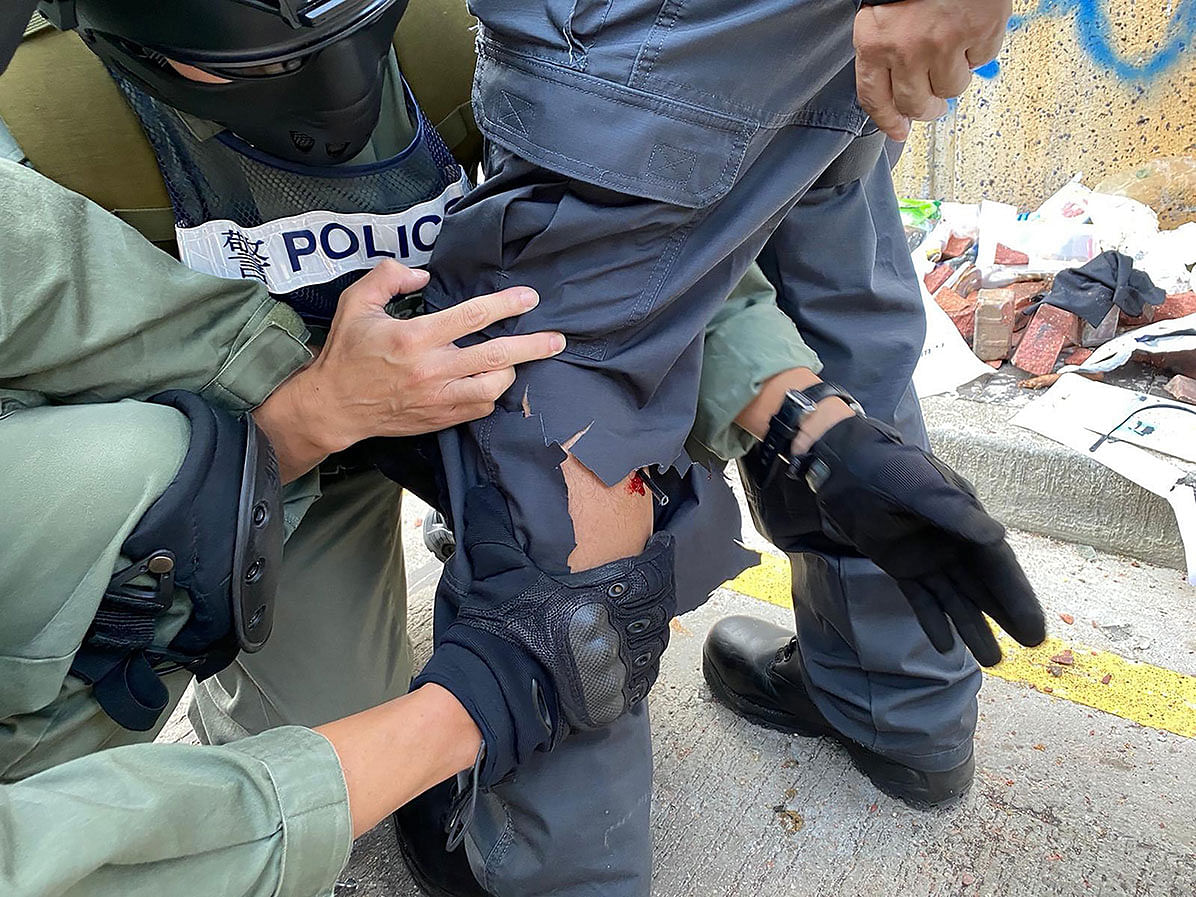 A handout taken by the Hong Kong police force shows police officers checking their colleague after he was struck in the leg by an arrow shot by a Hong Kong activist outside the Hong Kong Polytechnic University in Hong Kong on Sunday. Photo: AFP