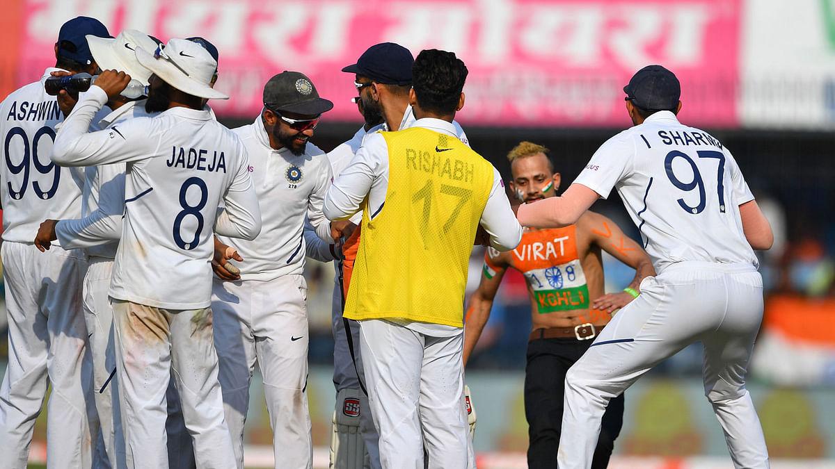 Indian cricketers react after a fan (2R) intruded into the playing area during the first Test cricket match of a two-match series between India and Bangladesh at Holkar Cricket Stadium in Indore on 16 November, 2019. Photo: AFP