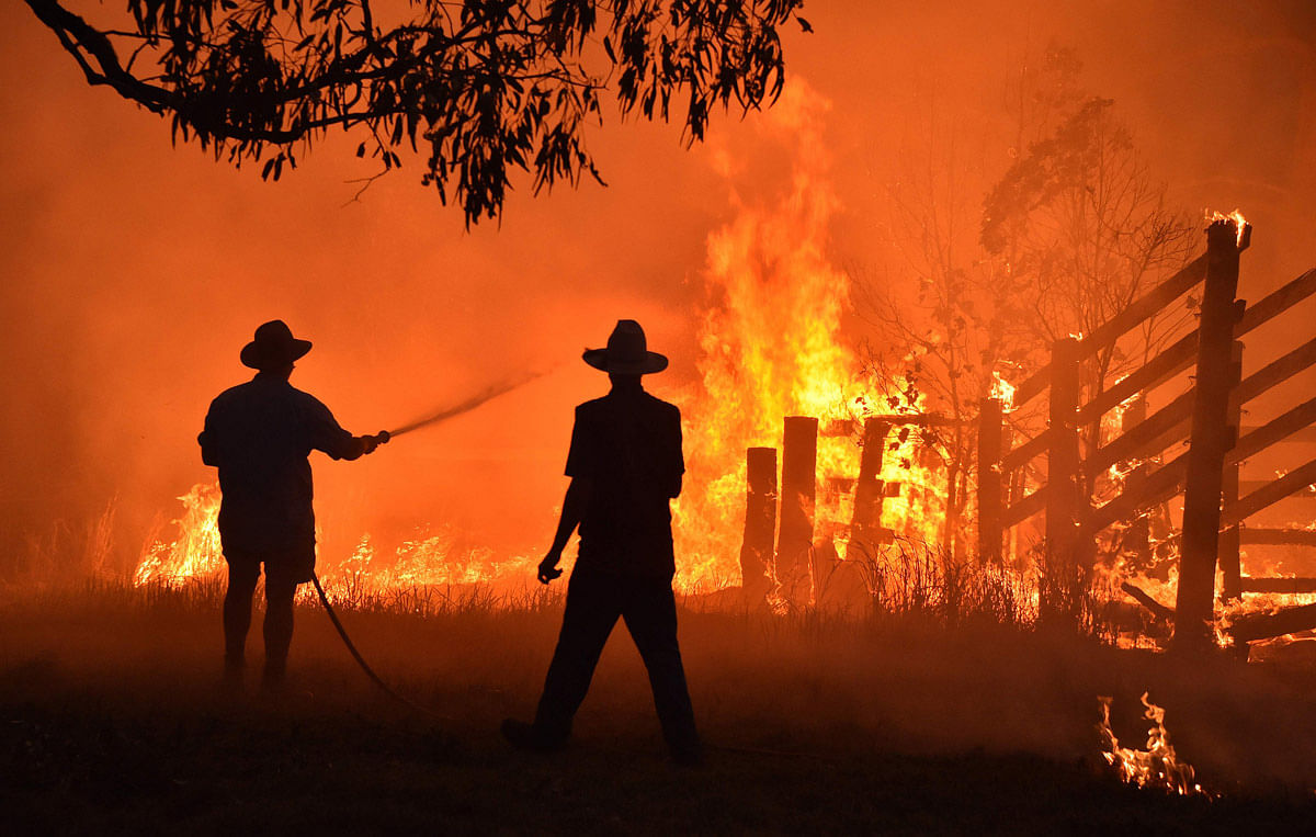Residents defend a property from a bushfire at Hillsville near Taree, 350km north of Sydney on 12 November. Photo: AFP