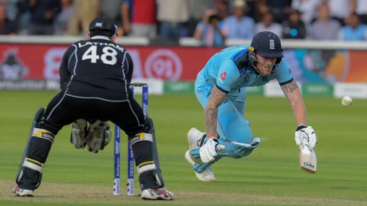 England`s Ben Stokes apologises after an attempted run out hits his bat and goes for four on 14 July 2019. Photo: AFP