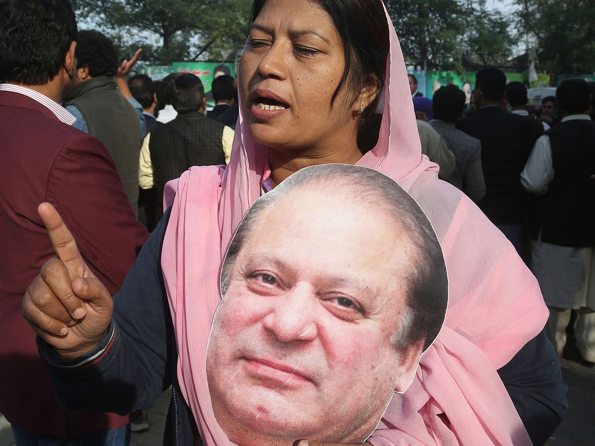 A supporter of Pakistan Muslim League Nawaz (PML-N) holds a cut out picture of the ailing former Pakistani prime minister Nawaz Sharif outside his residence before he travelled to Lahore airport prior to his departure for abroad for  medical treatment, in Lahore on 19 November 2019. photo: AFP