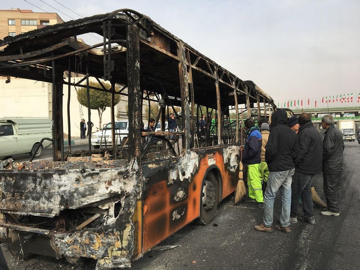 Iranians inspect the wreckage of a bus that was set ablaze by protesters during a demonstration against a rise in gasoline prices in the central city of Isfahan on 17 November. Photo: AFP