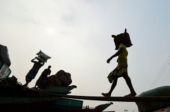 Workers unload goods on a boat on the banks of the Buriganga river in Dhaka on 19 November 2019. Photo: AFP