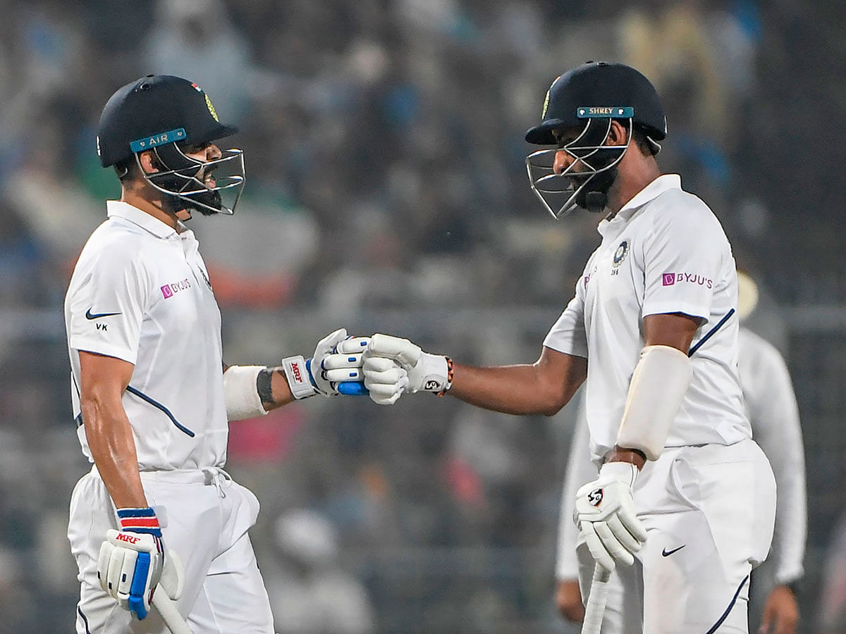 India`s cricket team captain Virat Kohli (L) and India`s Cheteshwar Pujara (R) celebrate a boundary during the first day of the second Test cricket match of a two-match series between India and Bangladesh at the Eden Gardens cricket stadium in Kolkata on 22 November 2019. Photo: AFP