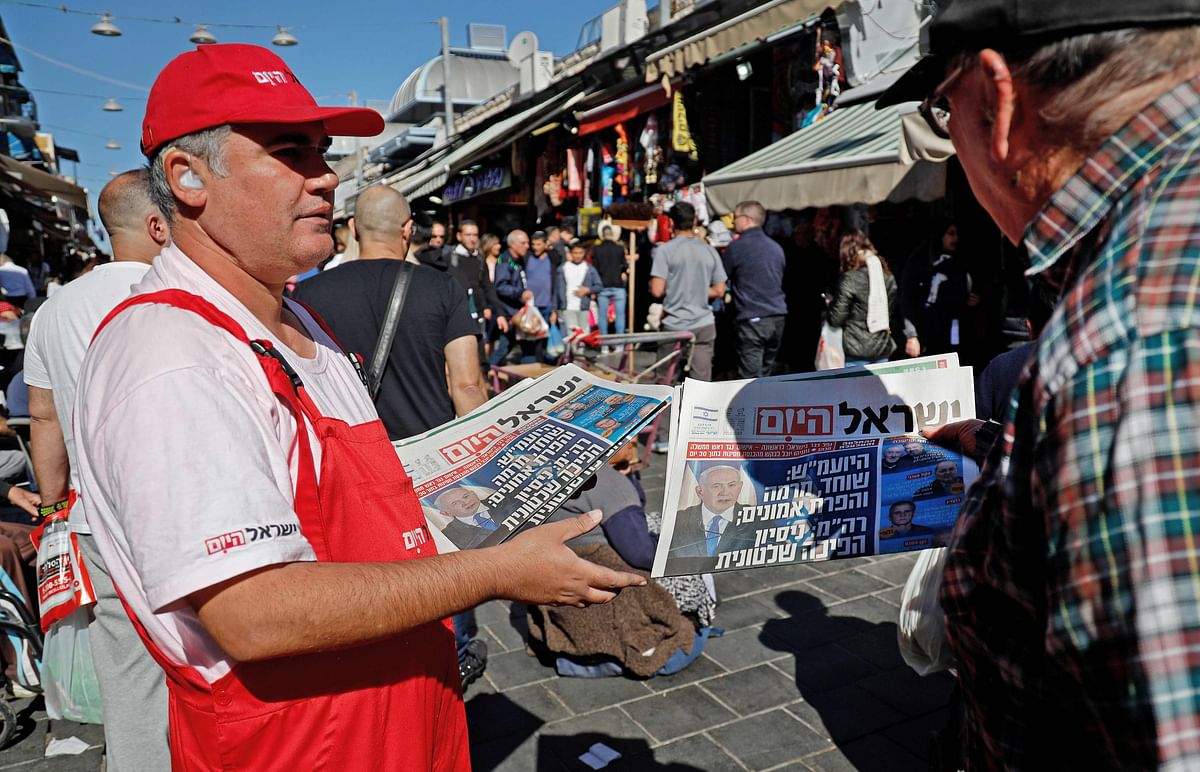 A man distributes copies of Israeli free daily Israel Hayom featuring on its front page news on Israeli Prime Minister Benjamin Netanyahu`s indictment, on 22 November 2019 in Jerusalem`s Mahane Yehuda market. Photo: AFP
