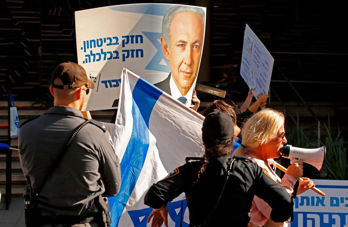 Supporters of Israeli prime minister Benjamin Netanyahu chant slogans and hold up signs in support of him during a counter-rally outside the Likud party headquaters in the coastal Mediterranean city of Tel Aviv on 22 November 2019, as Labour party supporters demonstrate against him nearby. Photo: AFP