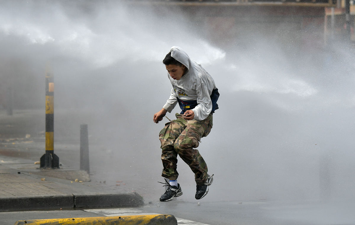 A demonstrator is hit by a riot police water cannon during a protest a day after a nationwide strike by students, unions and indigenous against the government of Colombia`s president Ivan Duque, in Bogota, on 22 November 2019. Photo: AFP