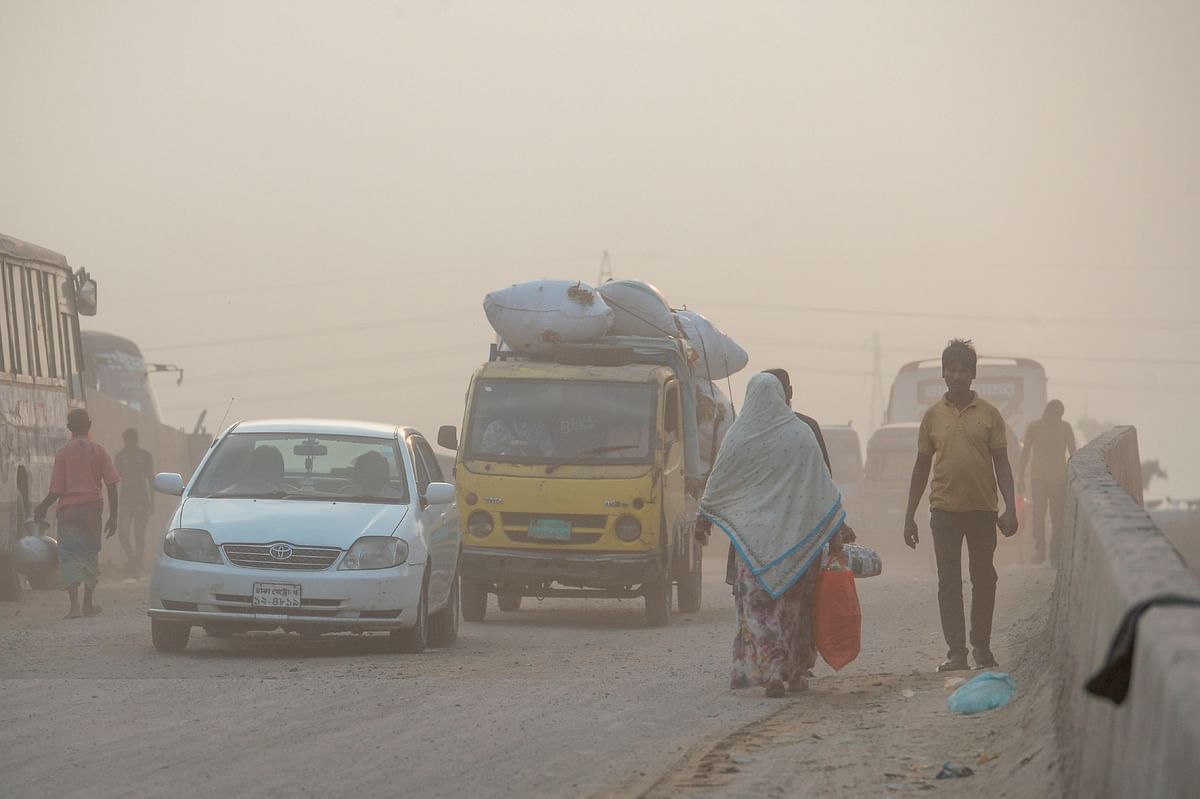 In this photo taken on 25 November 2019, motorists drive on a road as pedestrians walk on the side under heavy smog conditions in Dhaka. Photo: AFP