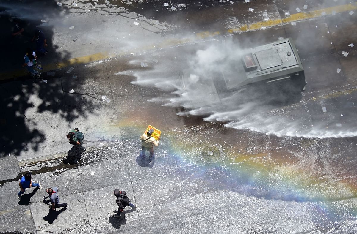 Demonstrators are sprayed by the police with a water cannon during a protest against the Chilean government, in Santiago on 26 November 2019. Photo: AFP