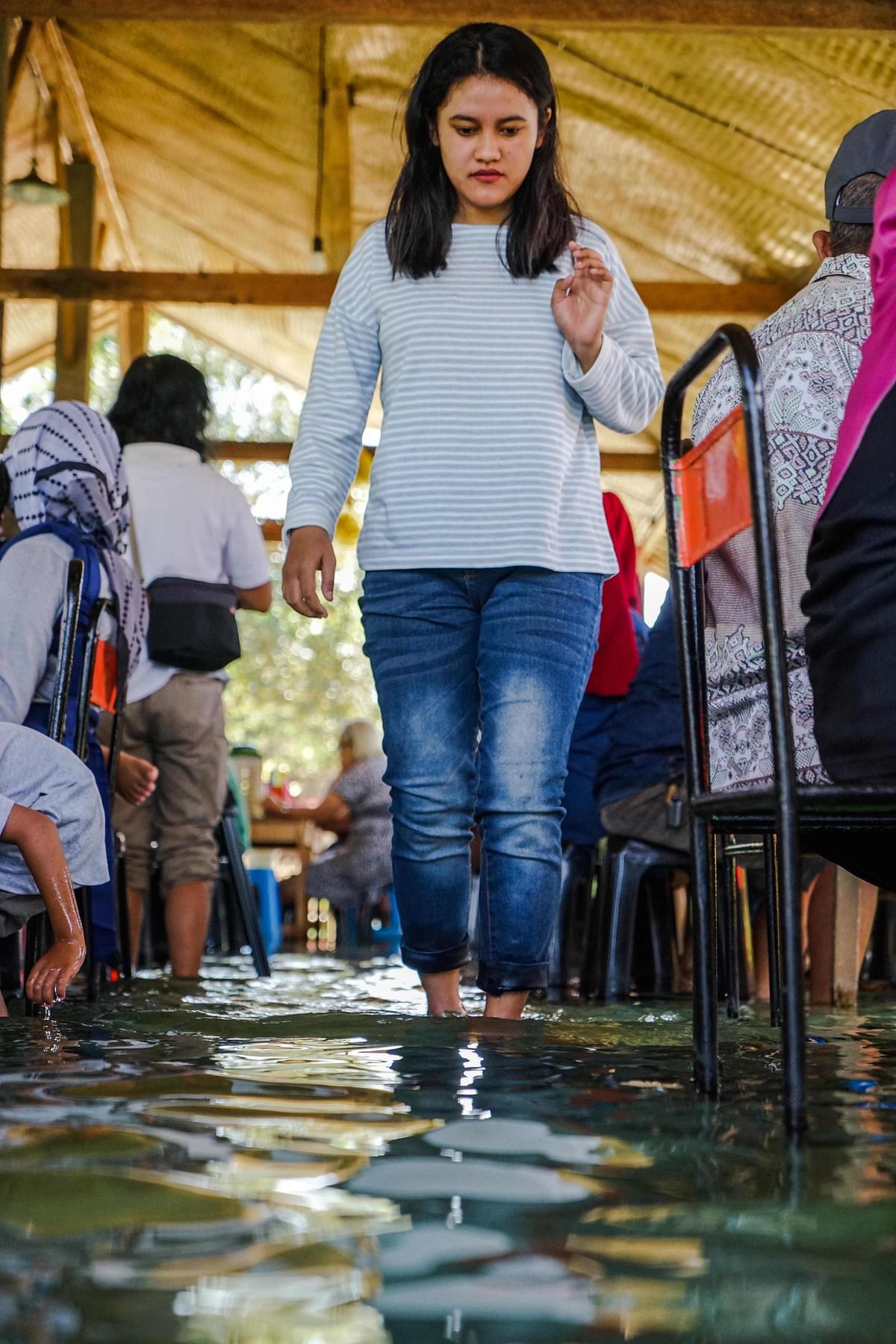 This picture taken on 15 November 2019 shows an Indonesian woman walking through water to her table to have lunch while fish bite her feet at a fish pool restaurant at Wedomartani village in Yogyakarta. Photo: AFP