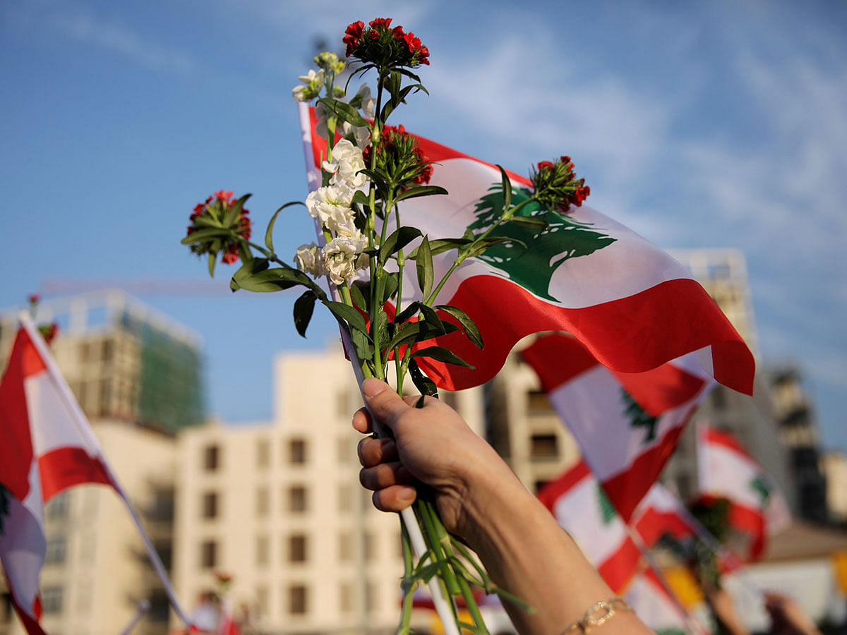 A woman marches holding a Lebanese flag and flowers during a parade, on the 76th anniversary of Lebanon`s independence, at Martyrs` Square in Beirut, Lebanon on 22 November 2019. Photo: AFP
