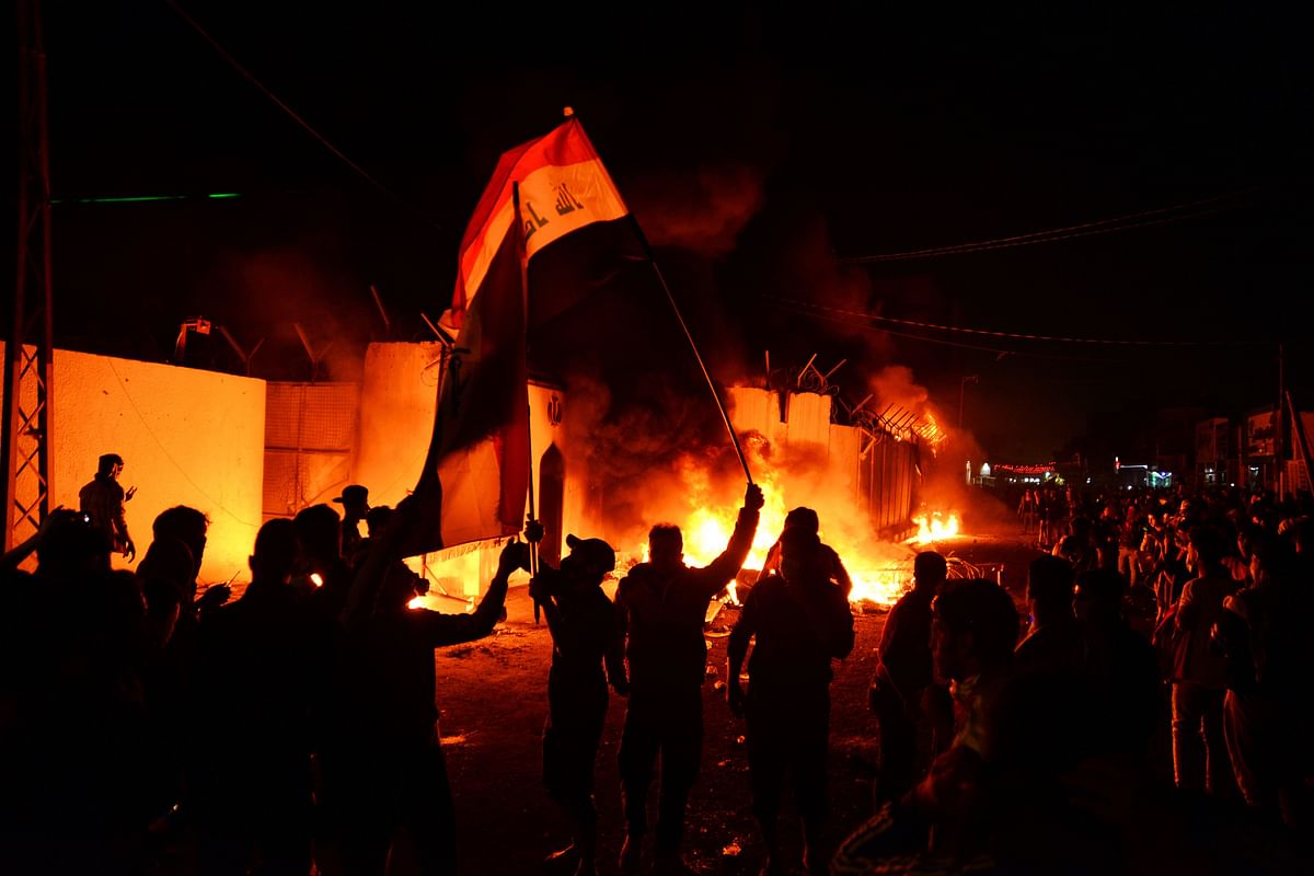 Iraqi demonstrators gather as flames start consuming Iran`s consulate in the southern Iraqi Shiite holy city of Najaf on November 27, 2019, two months into the country`s most serious social crisis in decades.