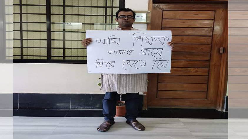 Dhaka University`s economics department teacher Rushad Faridi hold a placard which reads `I`m a teacher, let me go back to classroom`. Photo: UNB