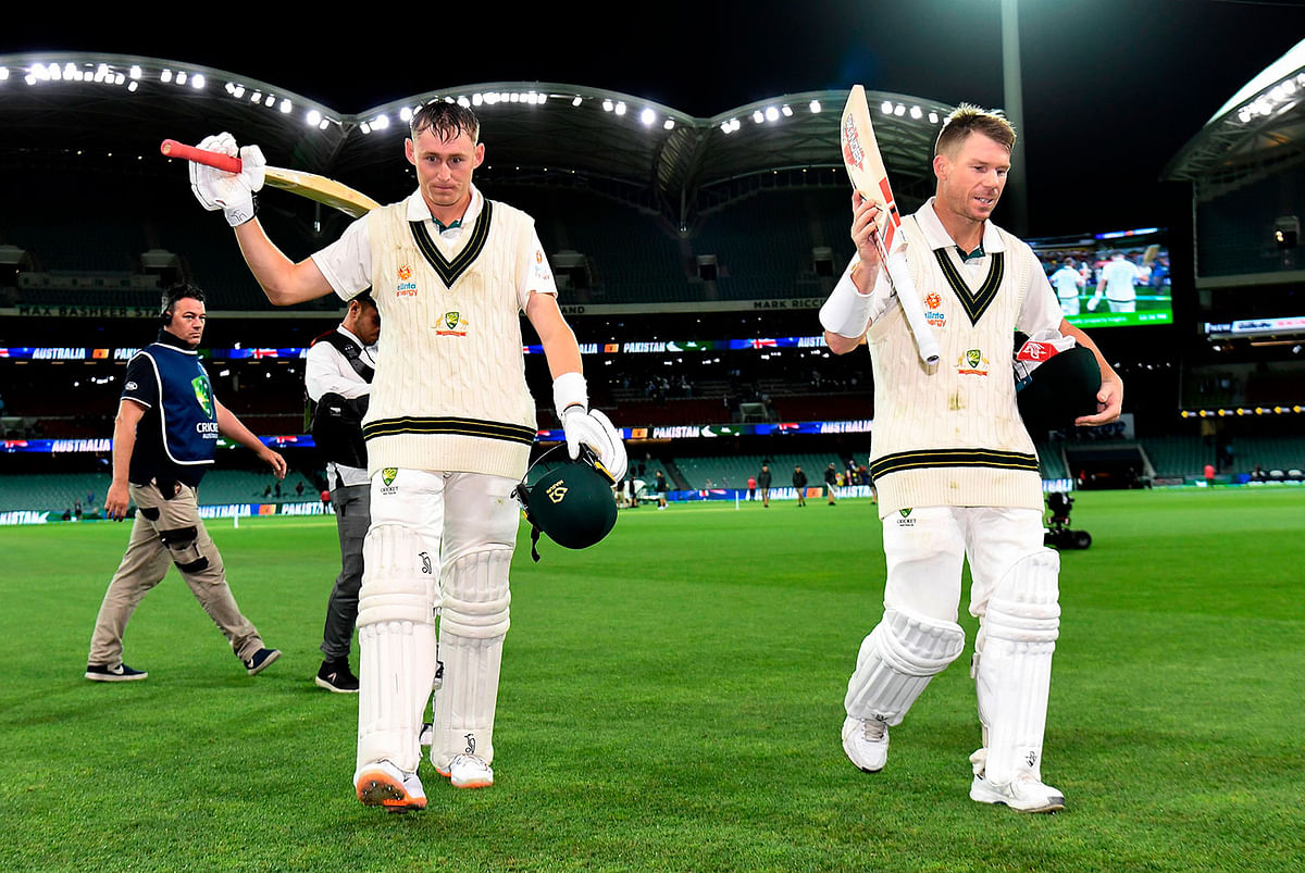 Australian batsmen Marnus Labuschagne (L) and David Warner (R) walk after their partnership against Pakistan on the first day of the second cricket Test match in Adelaide on 29 November, 2019. Photo: AFP.