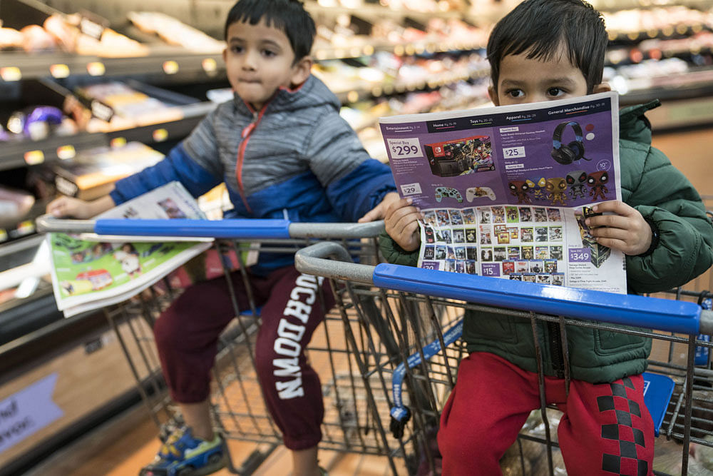 Brothers Abhishreyo Kundu, left, and Avigyan Kundu read the Black Friday circular as they shop with their parents in Walmart on Thanksgiving night ahead of Black Friday on November 28, 2019 in King of Prussia, United States. Photo: AFP