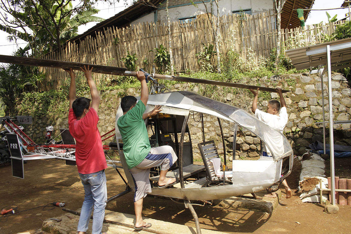 This picture taken on 17 November, 2019 shows Jujun Junaedi (R) working on his homemade helicopter in his backyard in Sukabumi. Photo: AFP