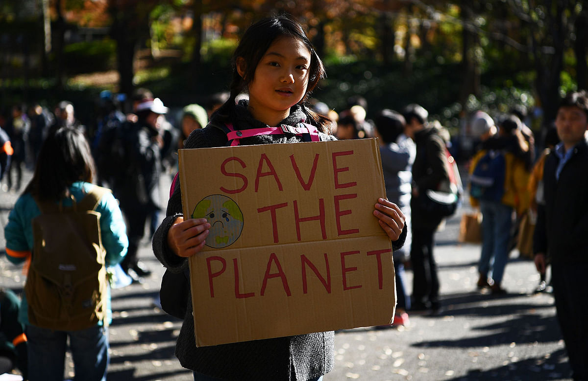 A girl holds a placard as she takes part in call for action on climate change with a couple of hundred people during a march in Tokyo on 29 November 2019. Photo: AFP