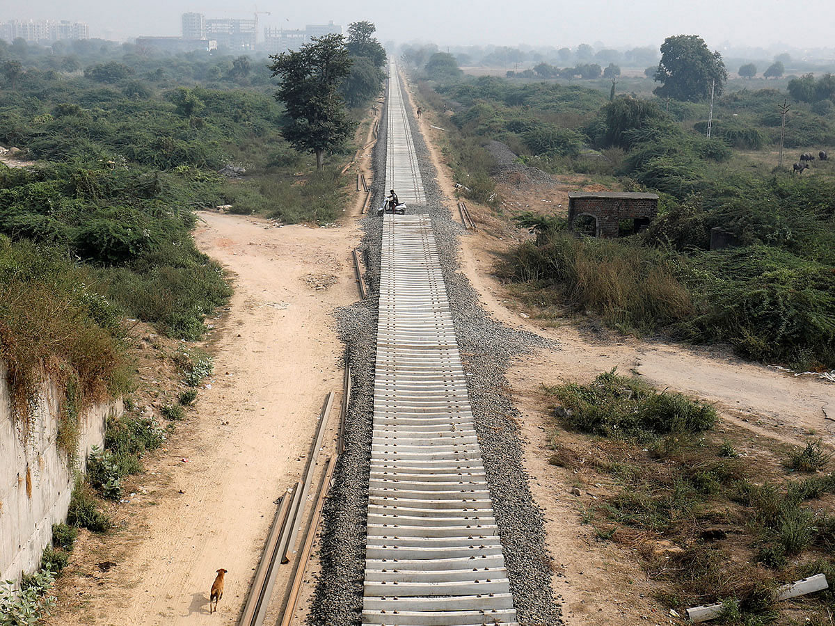 A man riding a scooter crosses an under-construction railway track at Sanathal, on the outskirts of Ahmedabad, India, on 29 November 2019. Photo: Reuters