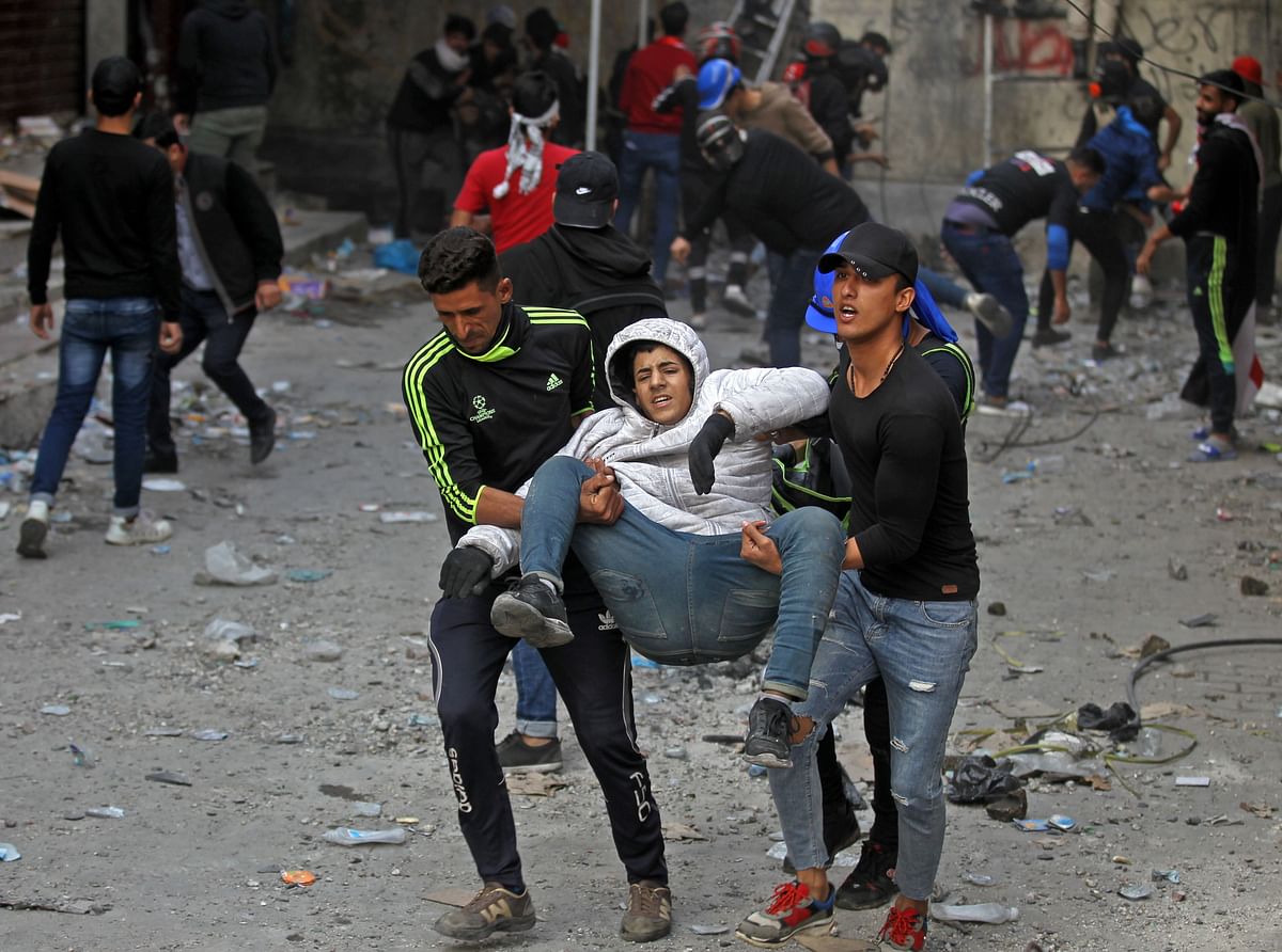 Iraqi anti-government protesters carry away an injured comrade amidst clashes with security forces by the capital Baghdad`s Rasheed street near al-Ahrar bridge on 29 November. Photo: AFP