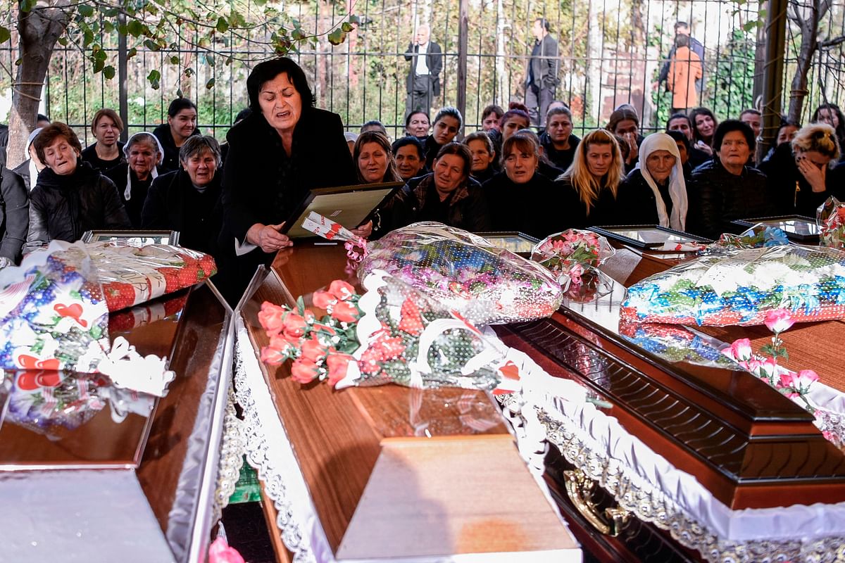 A relative mourns over the coffins of six members of the Cara family who died during the earthquake in Thumane, on 29 November 2019. Photo: AFP