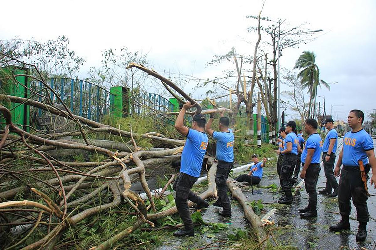 Policemen clear a road with fallen trees near the airport Legaspi City, Albay province, south of Manila on 3 December, after Typhoon Kamurri battered the province. Photo: AFP