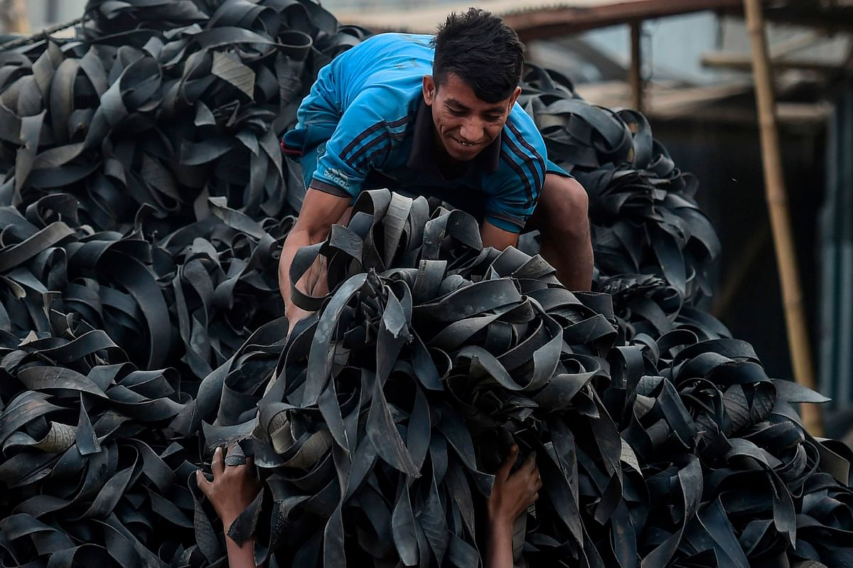 A labourer loads pieces of used tyres on a truck in Dhaka on 2 December 2019. Photo: AFP