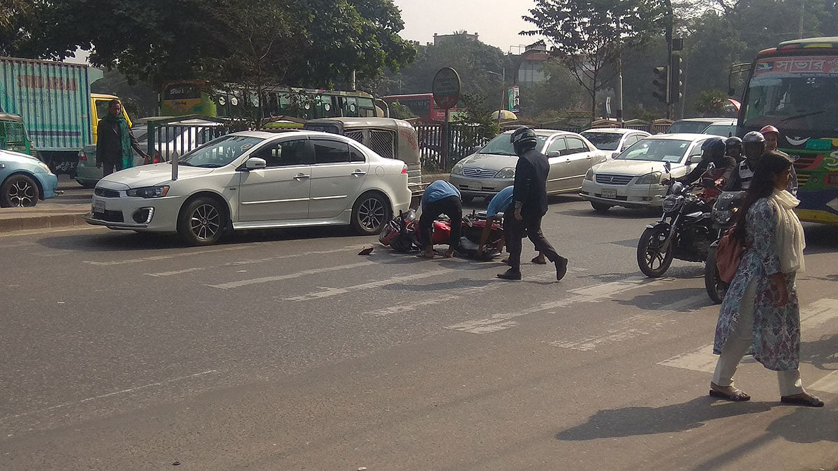People try to rescue a motorcycle on a busy road in Lalmatia in the capital after it hit a pedestrian at Mirpur Road, Manik Miah Avenue in Dhaka on 3 December 2019. Photo: Rajot Kanti Roy