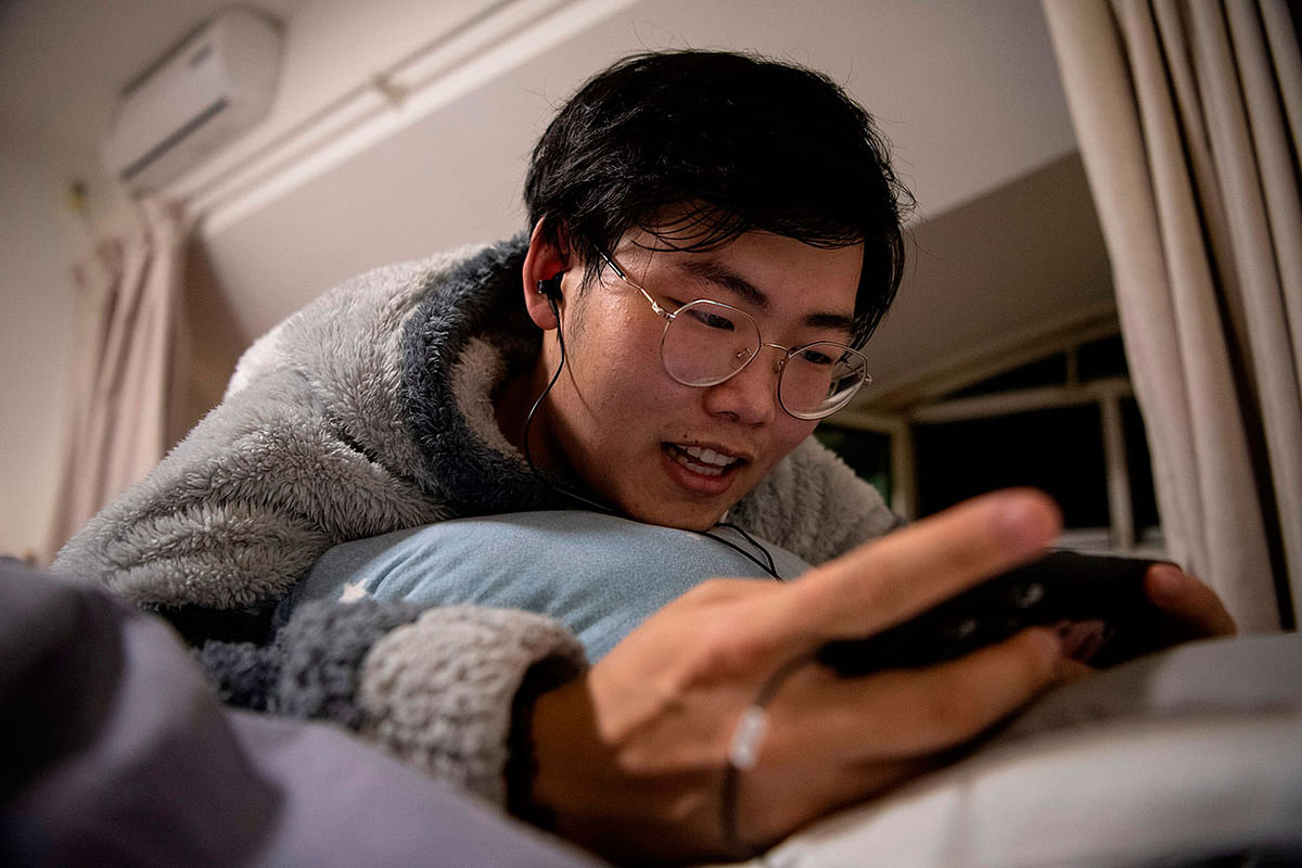 This photo taken on November 12, 2019 shows `virtual boyfriend` Zhuansun Xu, 22, talking to a girlfriend on his phone while playing a mobile game in his room in Beijing. Photo: AFP