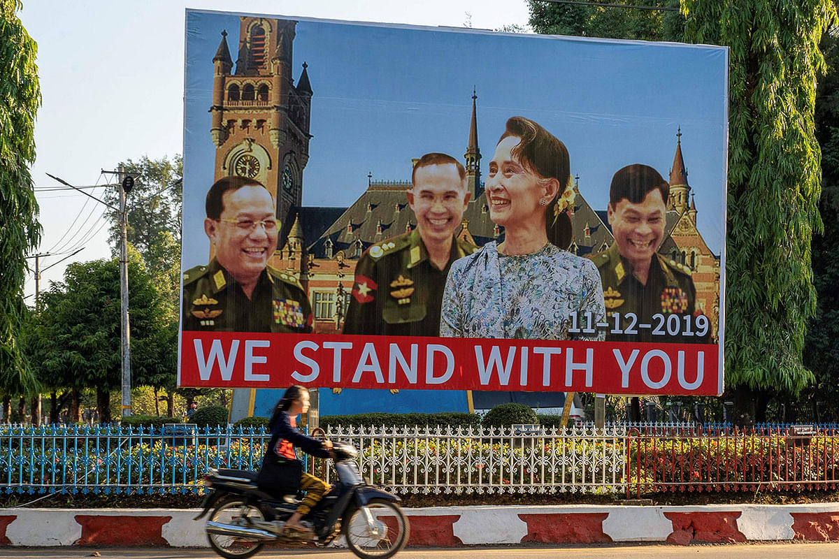A smiling Suu Kyi flanked by three green-clad soldiers laughing heartily underlined by the words `we stand with you`. Photo: AFP