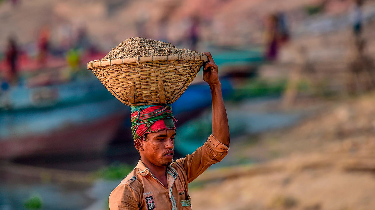 A labourer unloads building materials from a cargo ship in Gabtoli, on the outskirts of Dhaka on 3 December 2019. Photo: AFP