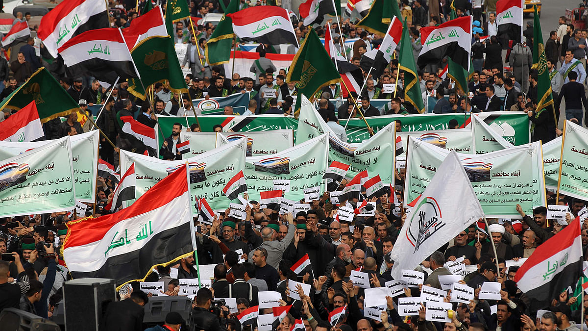 Iraqi demonstrators wave national flags and carry banners as the take part in an anti-government demonstration in the capital Baghdad`s Tahrir Square, on 6 December 2019. Photo: AFP