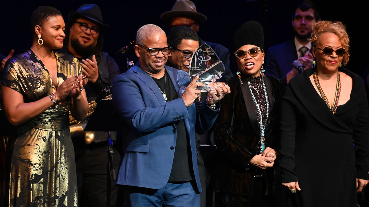 Renown trumpetist and composer Terence Blanchard hoists his Herbie Hancock Institute of Jazz 2019 Founder`s Award at the Kennedy Center in Washington, DC, on 3 December 2019 as vocalists Lizz Wright (L), Dee Dee Bridgewater and Cassandra Wilson (R) stand by. Photo: AFP