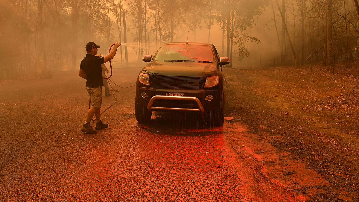 A local man hoses down fire retardant during a bushfire in Werombi, 50 km southwest of Sydney, Australia, on 6 December 2019. Photo: Reuters