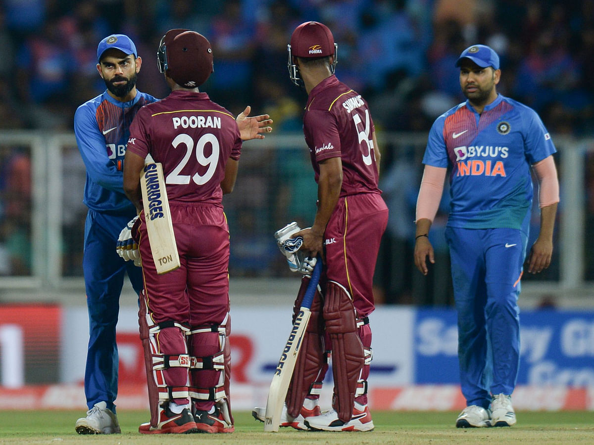 West Indies cricketer Lendl Simmons (R) and Nicholas Pooran (C) speak with Indian cricket captain Virat Kohli (L) after winning the second T20 international cricket match of a three-match series between India and West Indies at the Greenfield International Stadium in Thiruvananthapuram on 8 December 2019. Photo: AFP