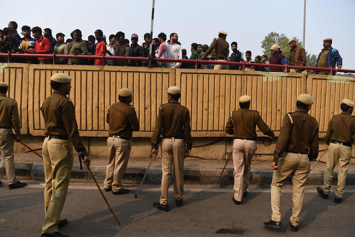 Police personnel move onlookers from a road after following a factory fire in Anaj Mandi area of New Delhi on 8 December 2019. Photo: AFP