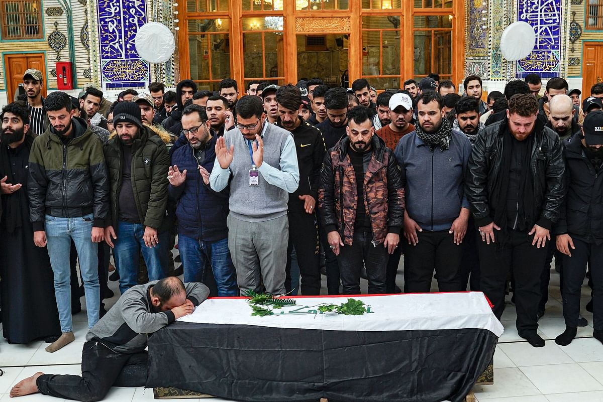 A man weeps by the coffin of an Iraqi protester and citizen journalist, who was killed during a demonstrations the previous day in Baghdad, as other mourners pray over his body during his funeral in the central holy Shiite shrine city of Najaf on 7 December. Photo: AFP