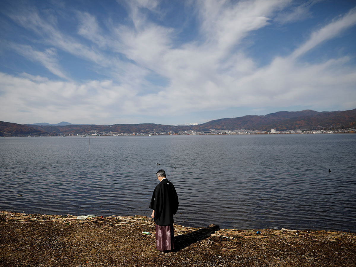 Kiyoshi Miyasaka, 69, a Shinto priest who oversees the Yatsurugi and Tenaga shrines, walks by the lakeside of Lake Suwa in Suwa, central Japan on 18 November. Photo: Reuters